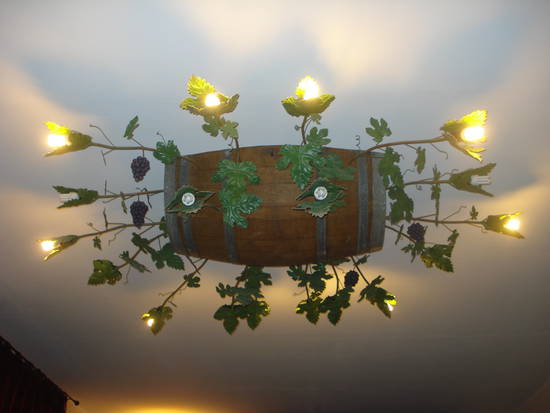 tralci, foglie e grappoli in ferro battuto escono da metà botte attaccata al soffitto